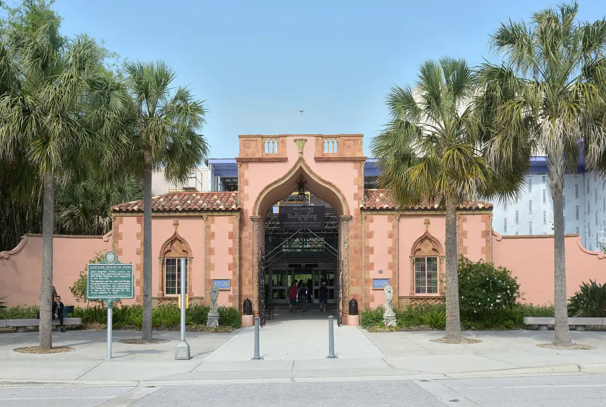 Pink Renaissance-style entrance gate of the Ringling Museum between palm trees