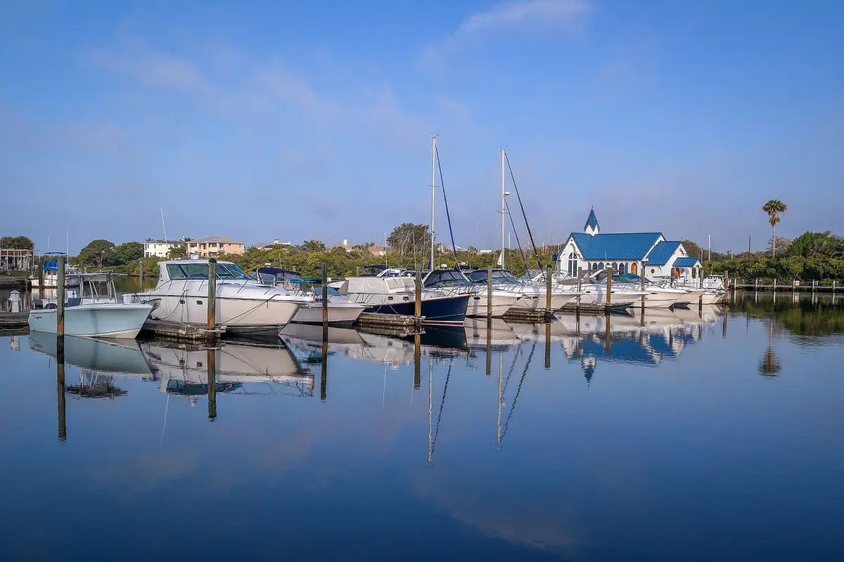 Sailboats and motor yachts moored in a calm marina with reflections