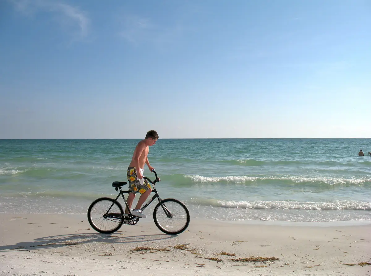 Cyclist riding a bike through shallow surf on a Gulf Coast beach