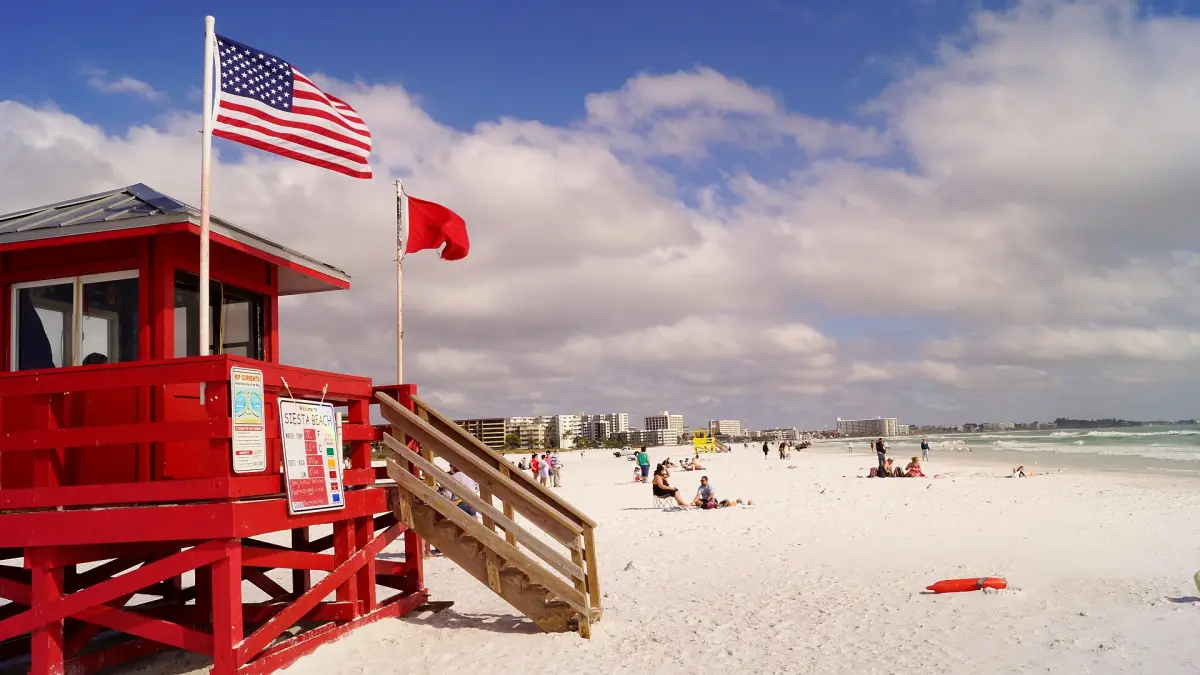 Red lifeguard stand with an American flag on the white sand of Siesta Key Beach