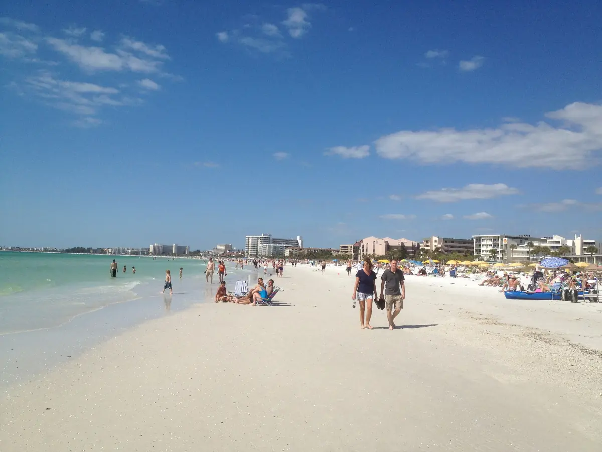 Spaziergänger am festen Uferstreifen mit Hotels und blauem Himmel dahinter
