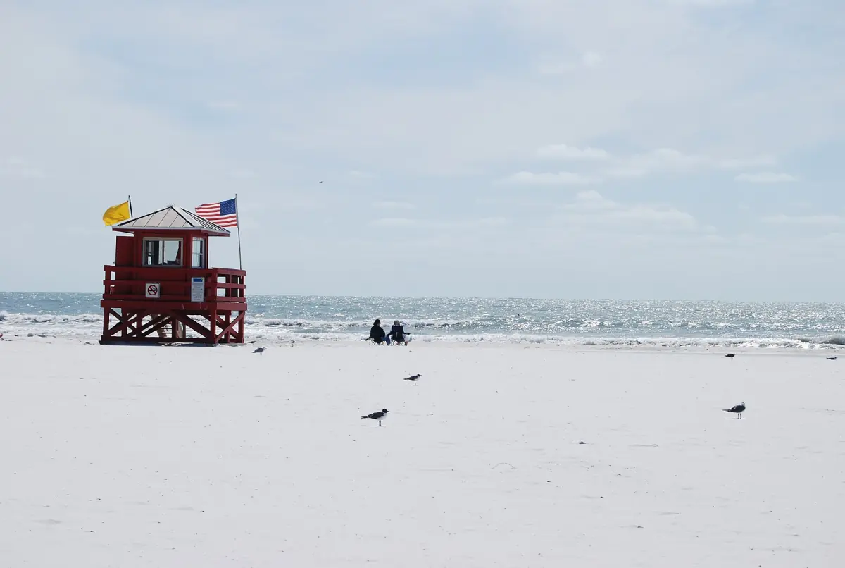 Wide white quartz sand beach with a lifeguard tower under a pale sky
