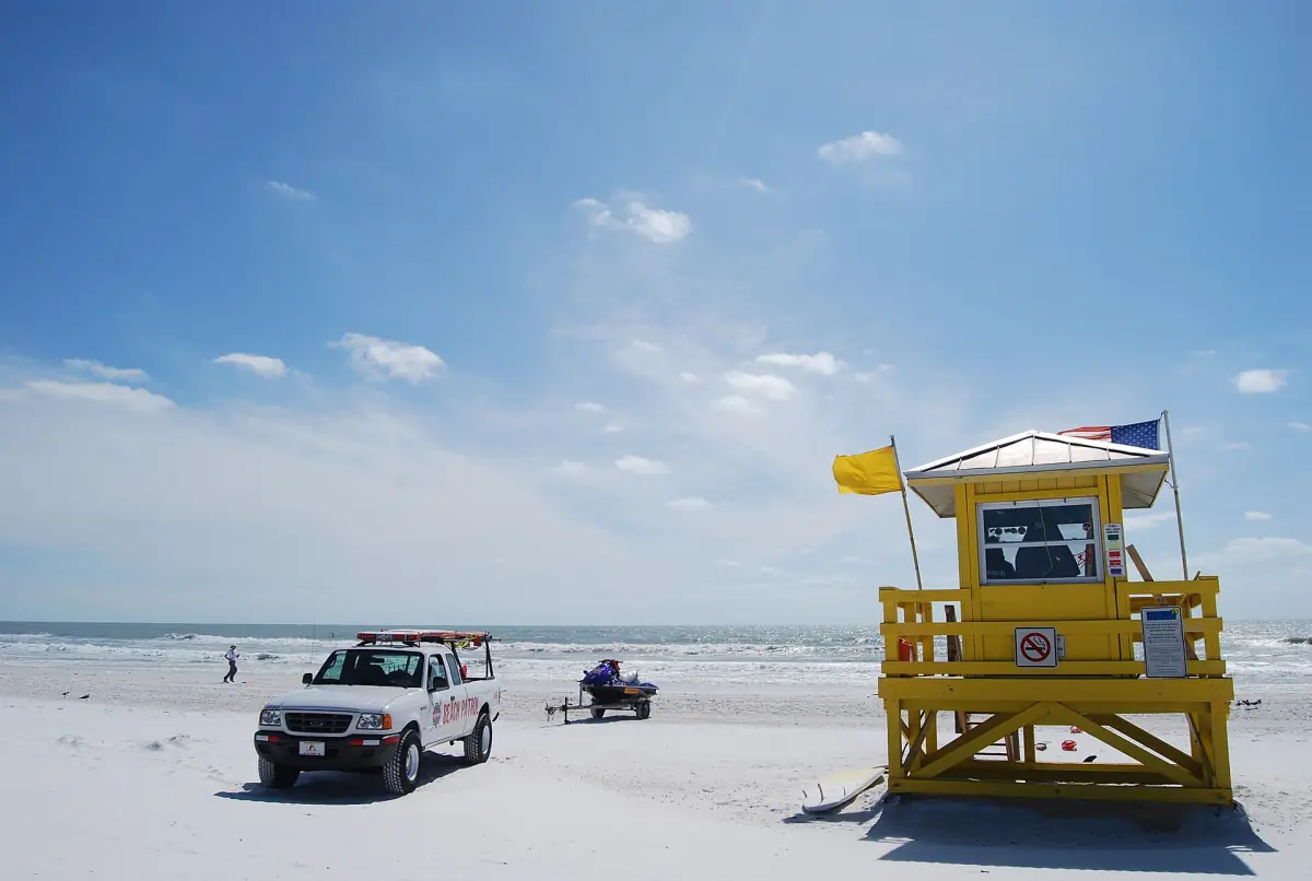 Yellow lifeguard tower and patrol truck on a sunny stretch of white sand