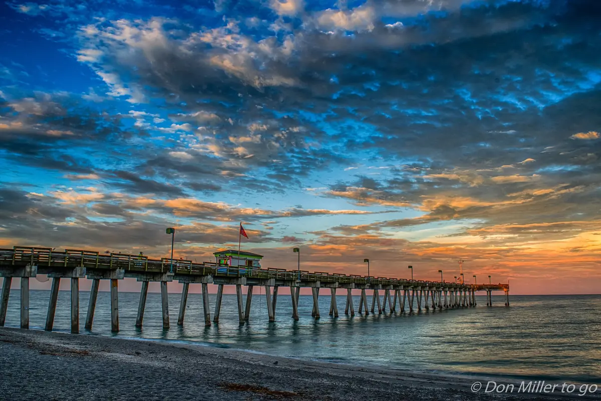 Wooden pier pilings in Venice at sunrise with blue and orange clouds